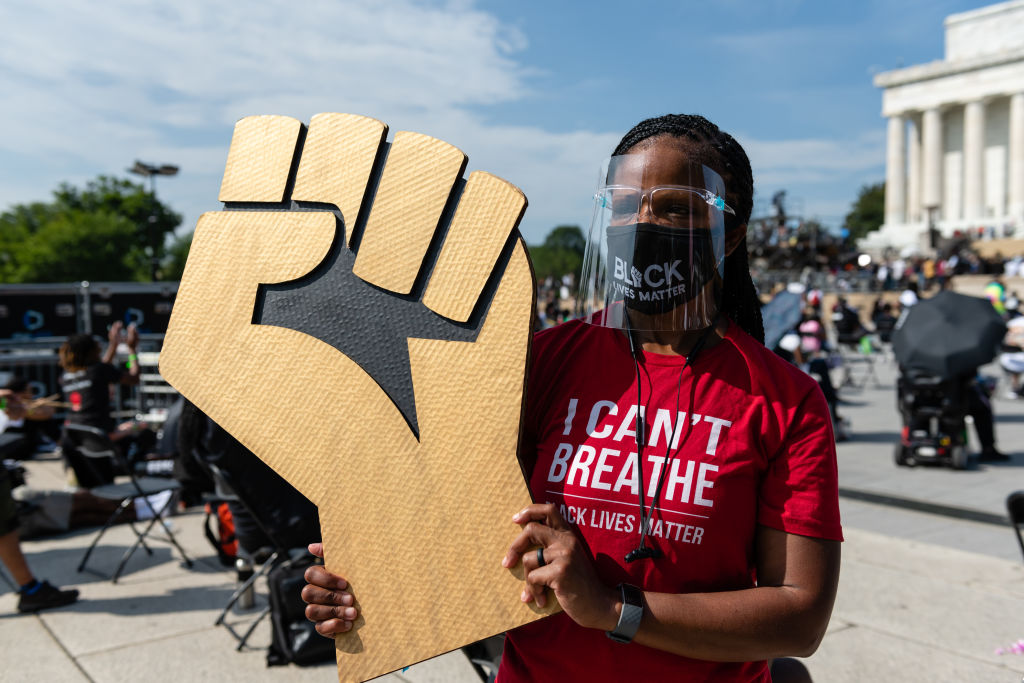 A demonstrator wears a protective mask and face shield during the "Get Your Knee Off Our Necks" March on Washington in Washington, D.C., U.S., on Friday, Aug. 28, 2020. The civil rights rally will be headlined by the Reverend Al Sharpton and is expected to bring thousands to the site where Reverend Martin Luther King Jr. delivered his historic "I Have a Dream" speech 57 years ago. Photographer: Eric Lee/Bloomberg via Getty Images